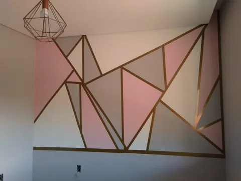 Parede adesivada com desenho geométrico rosa e dourado