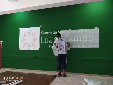 Instalador da MV Print aplicando letreiro de recorte numa parede verde